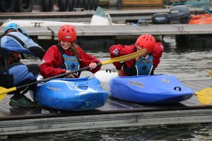 Two women getting into canoes