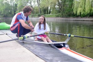 A coach talking to a female rower on a river.