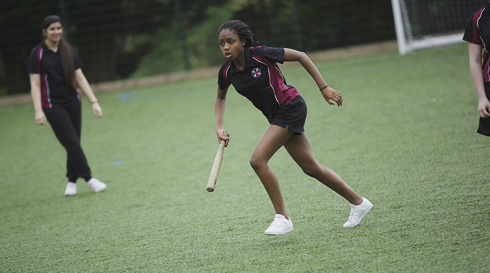 A girl running with a rounders bat