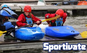 A boy and girl sat in 2 canoes waiting to go into the water.