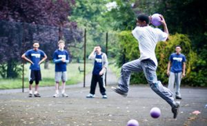 A teenage boy playing handball in his school play ground.